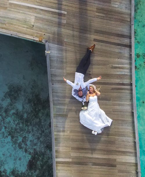 Free Photo of Bride and Groom Laying on Pier Stock Photo