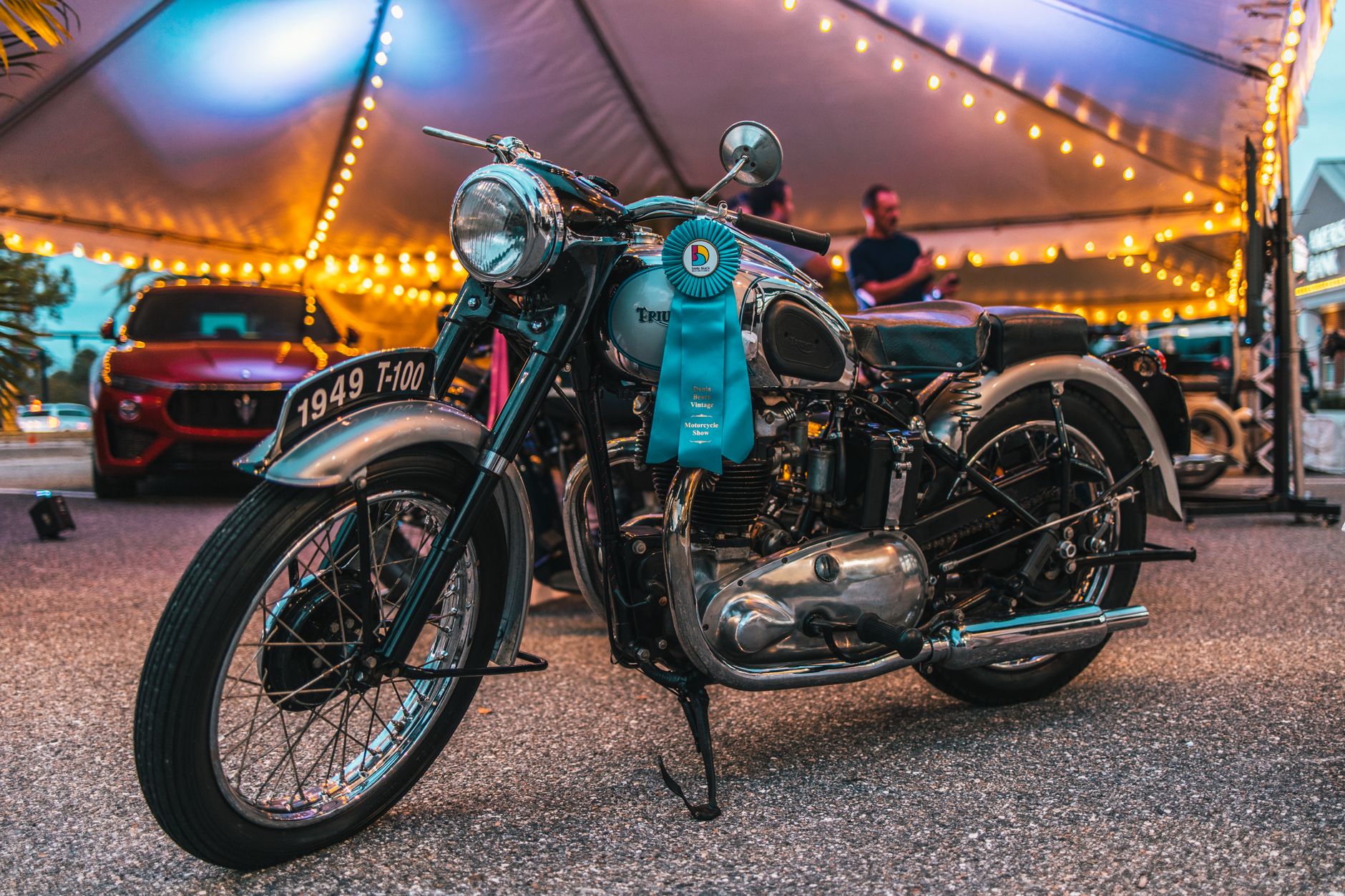 A classic 1949 Triumph T100 motorcycle displayed at an outdoor event, showcasing its vintage charm.