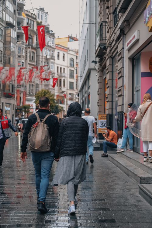 Free A couple walking on a rainy day in a lively Istanbul street with Turkish flags overhead. Stock Photo