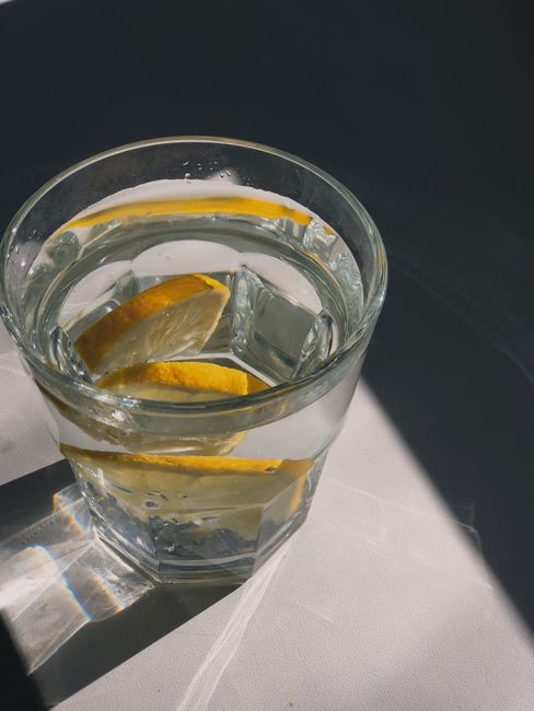 A close-up of a refreshing glass of water with lemon slices, bathed in warm sunlight.