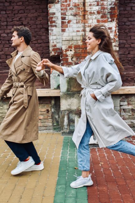 Happy couple holding hands and running in Lviv, Ukraine against a brick wall.