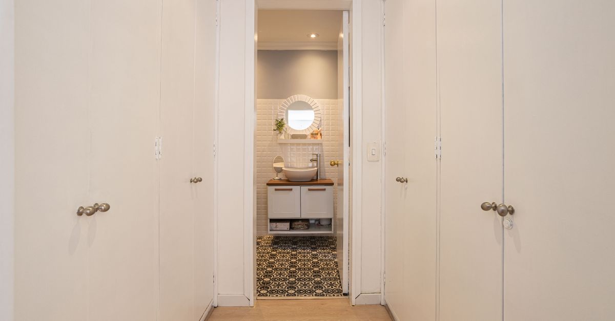 Elegant narrow hallway with white closets leading to a stylish bathroom featuring modern decor in Bogotá.