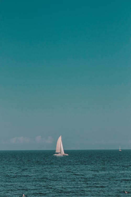 White Sailboat on Sea Under Blue Sky