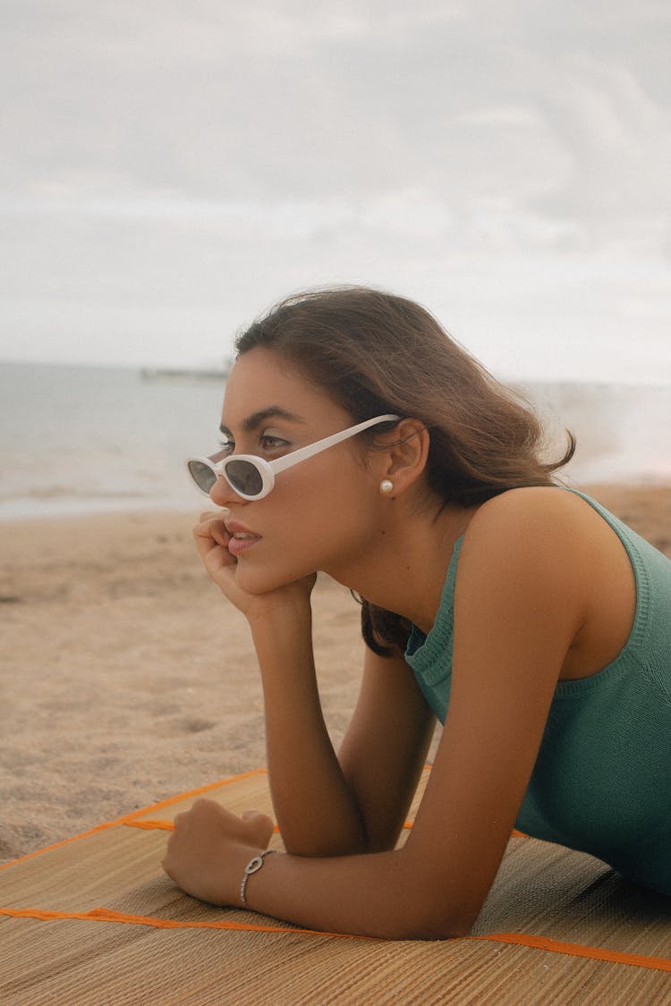 Woman In Sunglasses Laying On Bamboo Mat On Sand