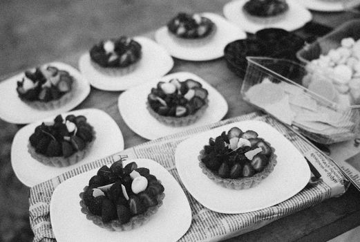 Black and white image of strawberry tarts on plates, showcasing delicious pastries.