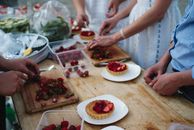 People Making Strawberry Tartlets on Wooden Table