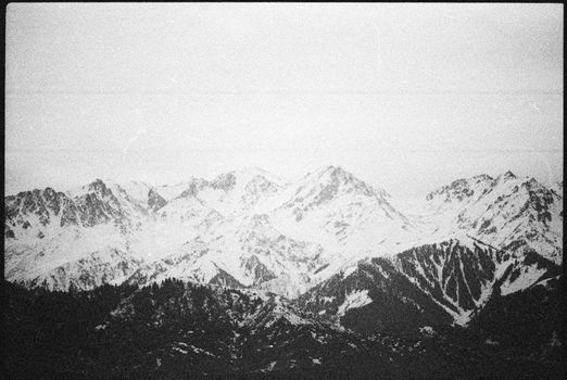 Vintage-style black and white photo of a snowy mountain range in winter.