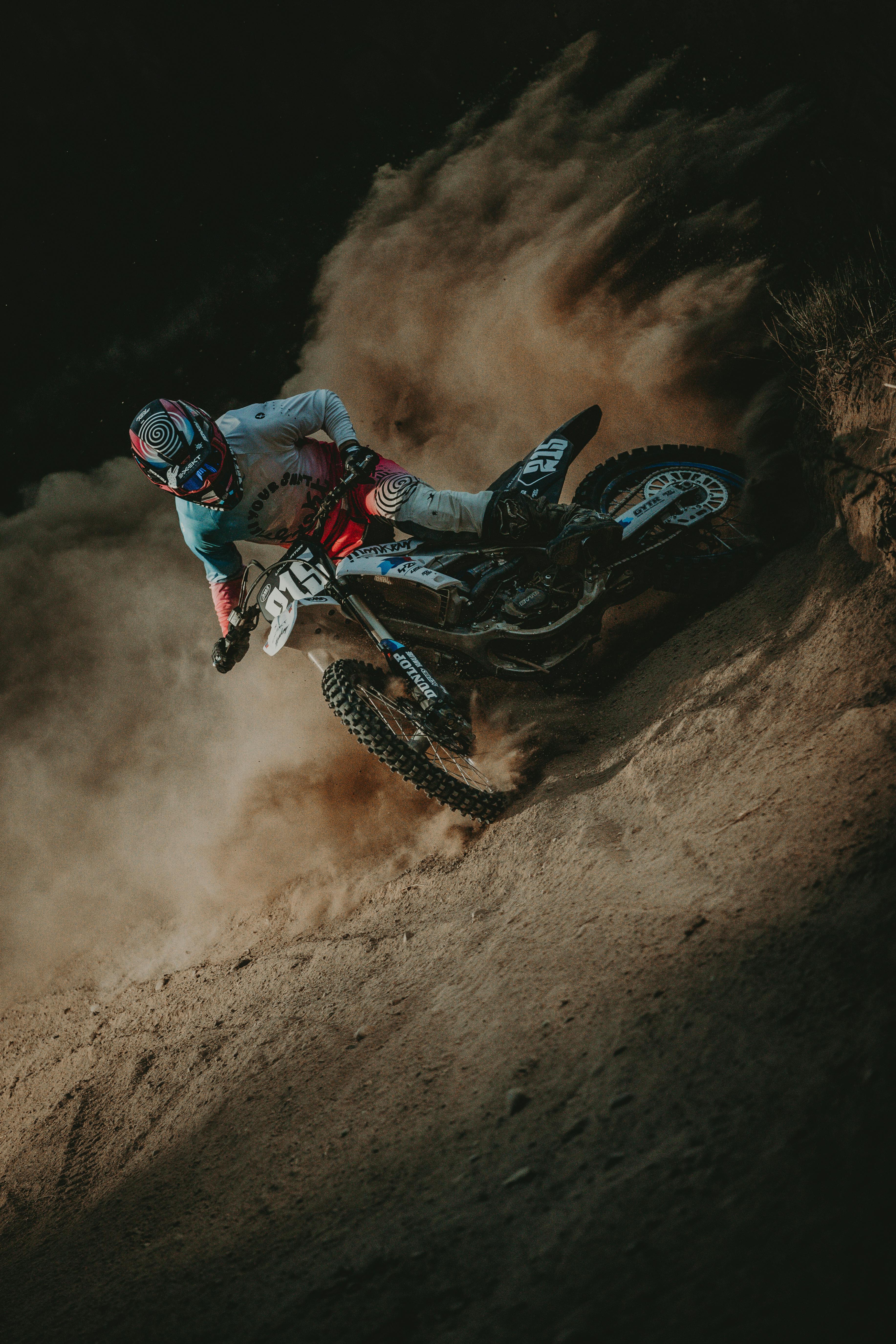 Thrilling motocross action as a racer accelerates on a dusty trail during the day.