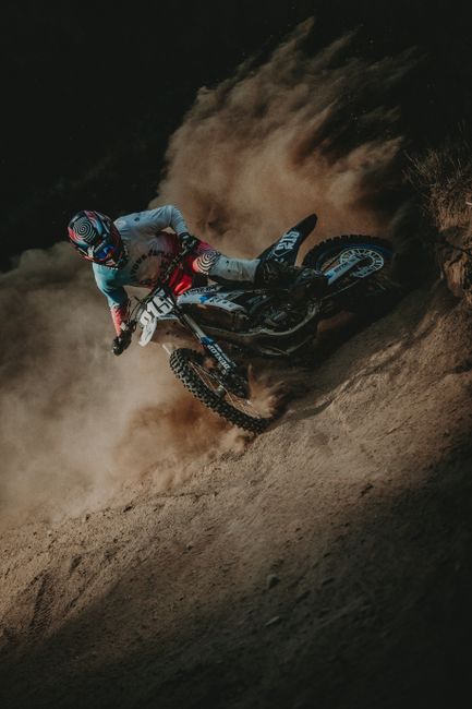 Thrilling motocross action as a racer accelerates on a dusty trail during the day.