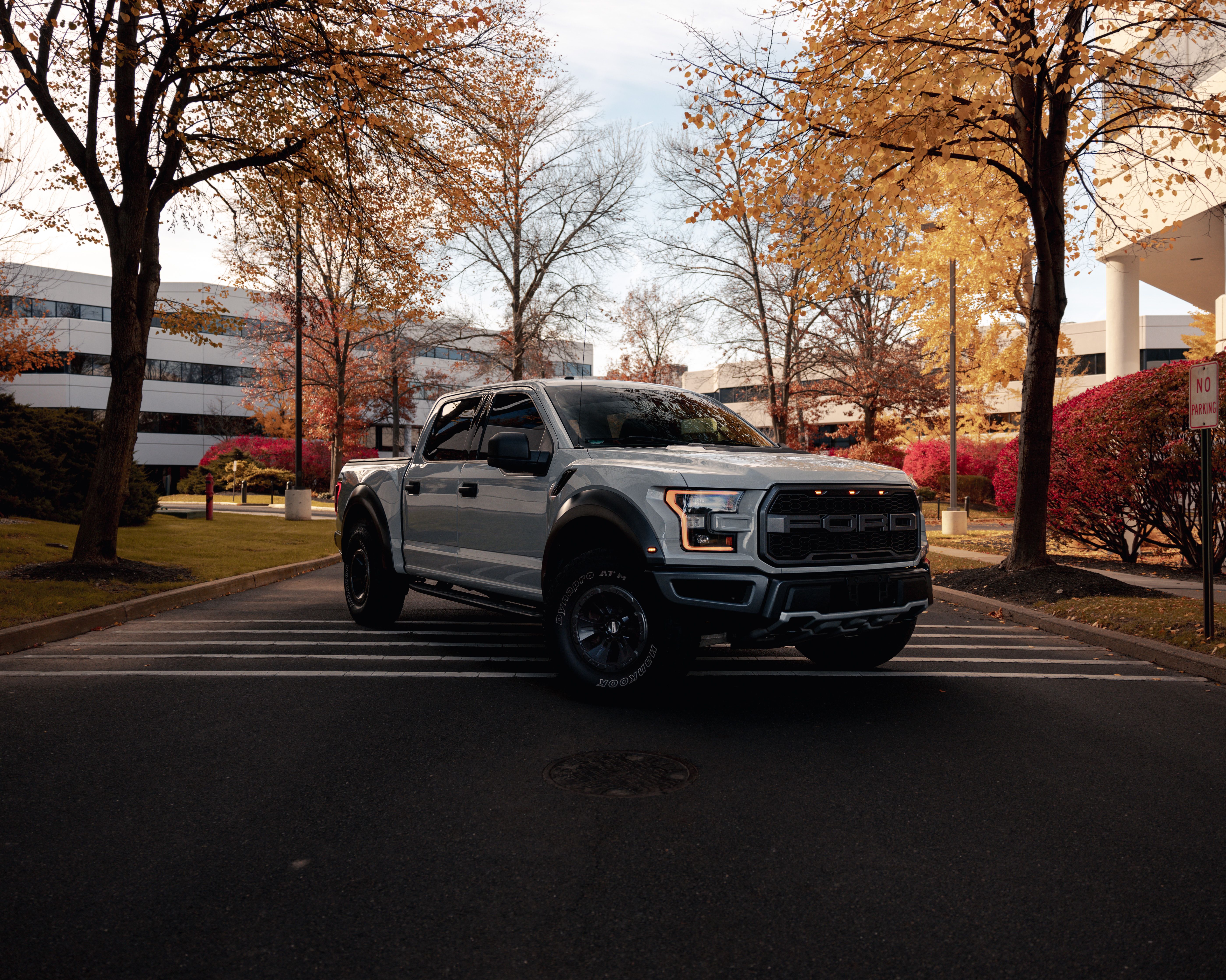 A modern pickup truck parked on an urban street surrounded by autumn trees representing seasonal driving in Canada