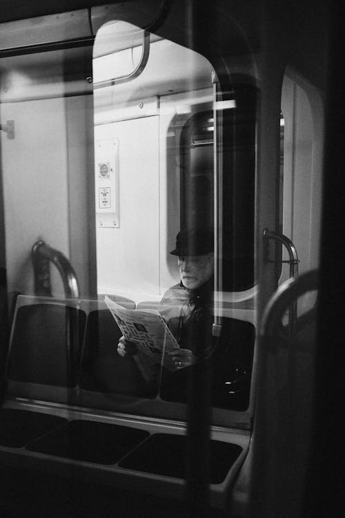 Man in Black Jacket Reading Newspaper in Front of Mirror