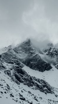 Dramatic snowy mountain peaks covered in fog, capturing the essence of winter.