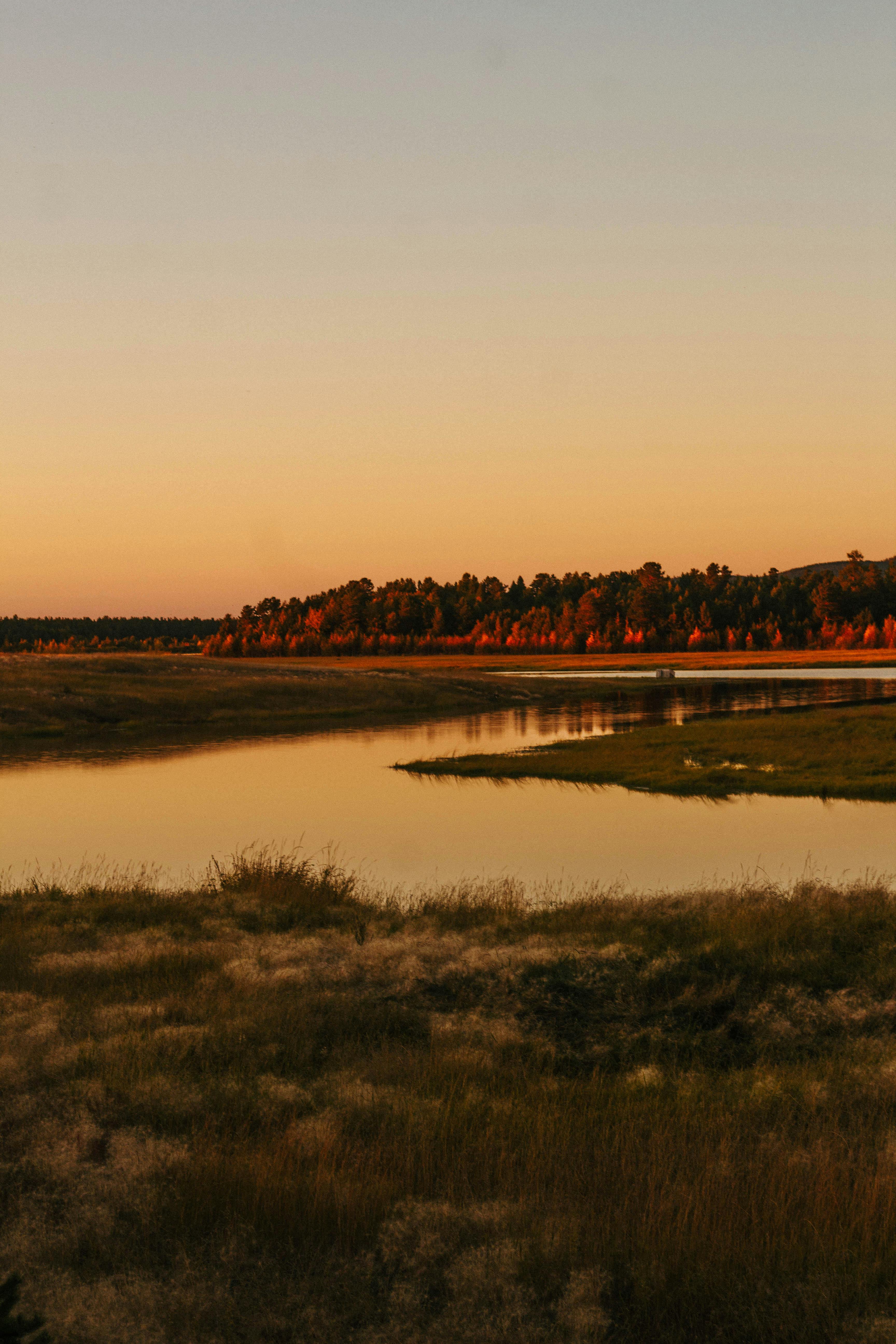 Peaceful river scene with glowing sunset reflecting on the water.