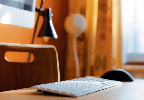 Free Close-up of a clean desk setup featuring a wireless keyboard and mouse on a wooden table. Stock Photo