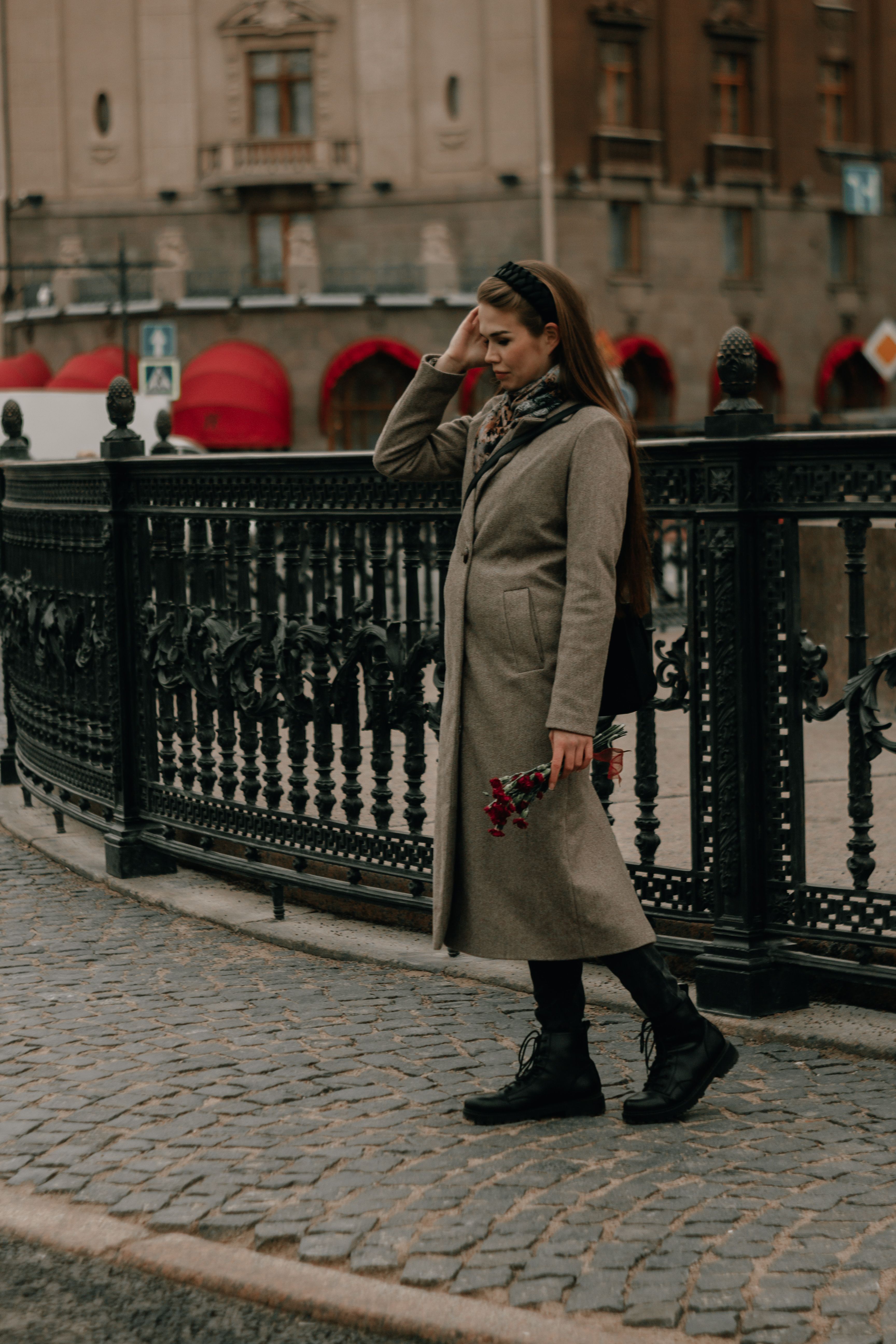 Woman in Brown Coat Standing Near Black Metal Fence · Free Stock Photo