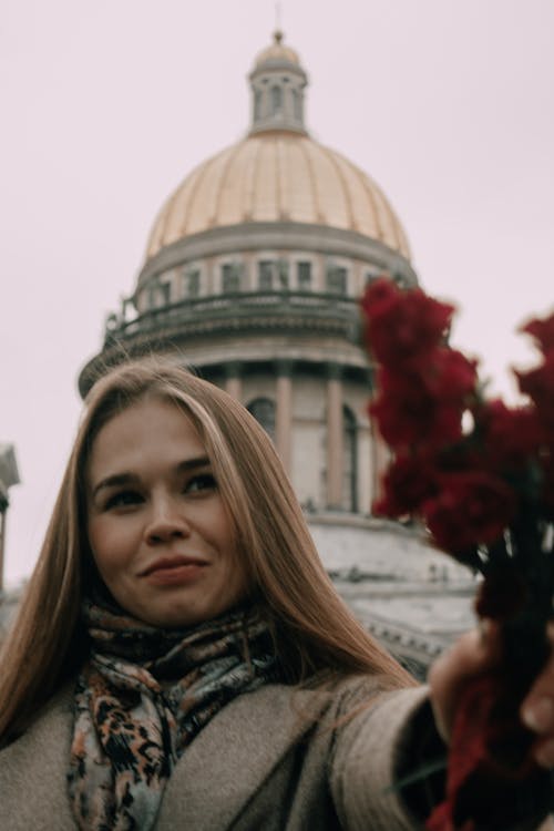 Blonde Woman Holding Out Flowers in Front of the St Pauls Cathedral in London, England