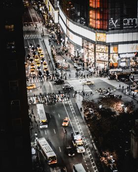 夜晚，一个繁忙的城市十字路口被从高处拍摄下来，画面中有汽车、公共汽车和行人