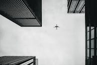 从低视角捕捉飞机在城市摩天大楼上方翱翔的景象