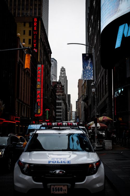 Free Urban street view featuring a police car under city lights and tall buildings. Stock Photo