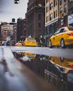 充满活力的城市街道上，黄色的出租车穿梭其间，水坑映照着历史建筑