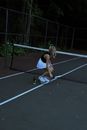 Woman in Black Tank Top and Blue Denim Shorts Sitting on Tennis Court