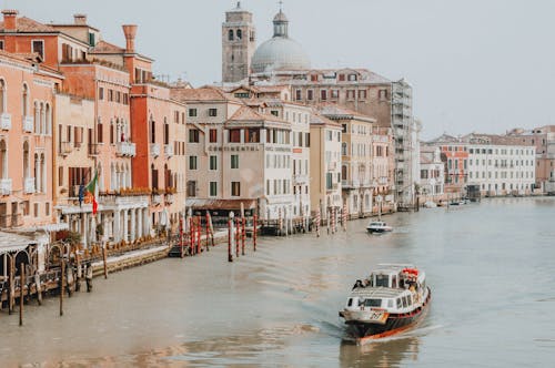 Free White Boat on Water Near Concrete Buildings Stock Photo