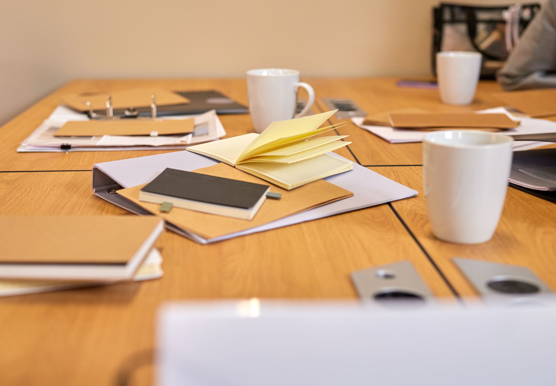 An overhead view of a tidy desk with notebooks and coffee mugs in an office setting.