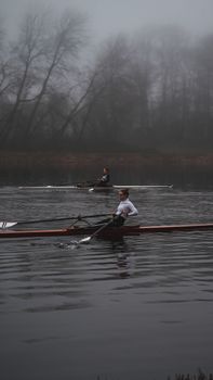 Two athletes rowing across a misty lake, showcasing the serenity of water sports.