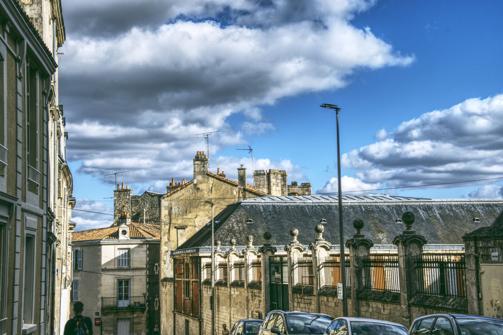 Immeubles de pierre et toits d'ardoise aux cheminées sous des nuages spectaculaires