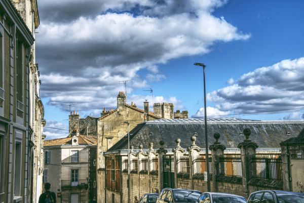 Immeubles de pierre et toits d'ardoise aux cheminées sous des nuages spectaculaires