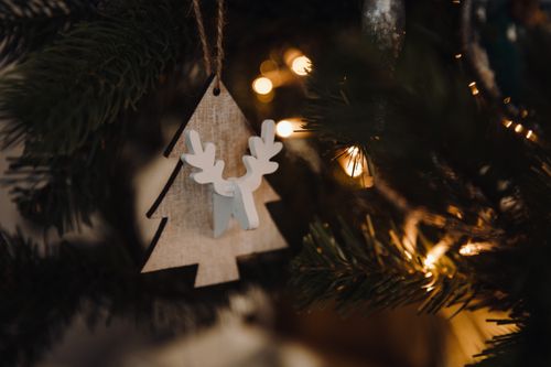 Free Close-up of a wooden Christmas tree ornament with lights, creating a warm festive atmosphere. Stock Photo