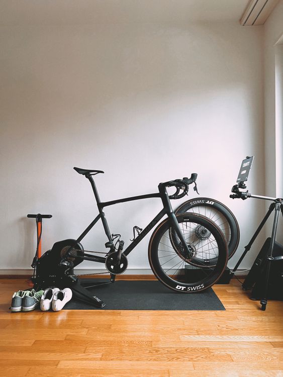 Minimalist indoor cycling setup featuring a sleek road bike and sports equipment for virtual training — illustrates trainer types comparison