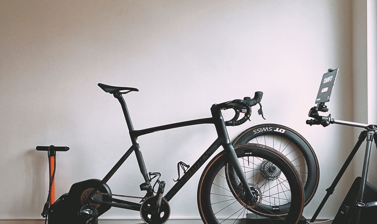 Minimalist indoor cycling setup featuring a sleek road bike and sports equipment for virtual training — illustrates trainer types comparison