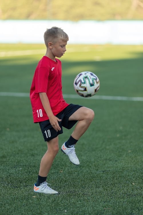 A Boy Playing Soccer Ball on the Soccer Field