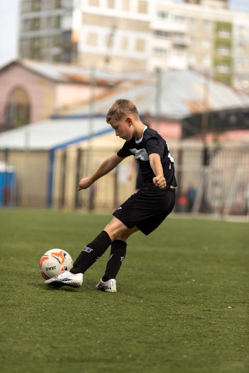 Free Boy in Black Jersey Playing Soccer Stock Photo