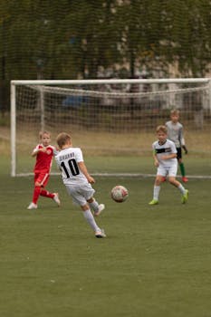 Young boys playing soccer on an outdoor field during the day. Action shot with goalpost.