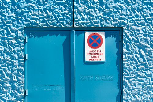 Free Bright blue textured wall with warning sign and exit door. Stock Photo