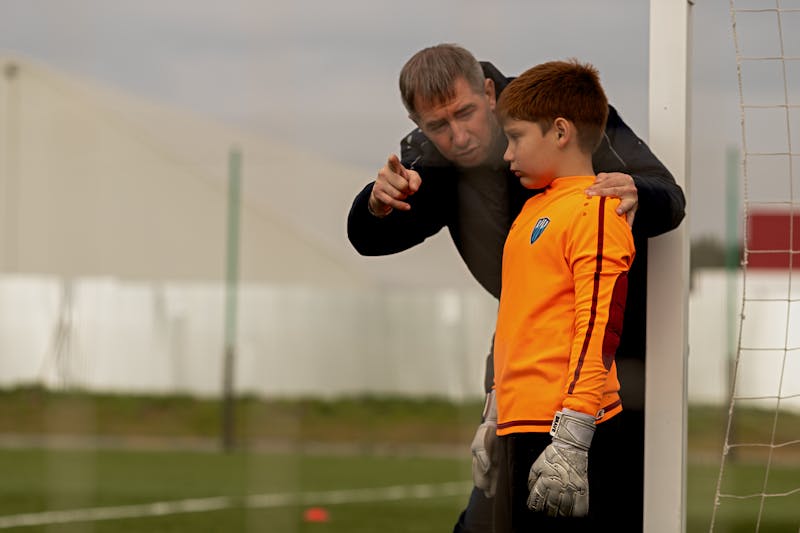 マンツーマンでサッカーを教えるコーチ