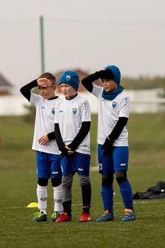 Three young boys in soccer uniforms stand together on a grassy field during a match.