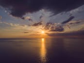 宁静的海面上，日落时分的水域倒映着天空中戏剧性的云层