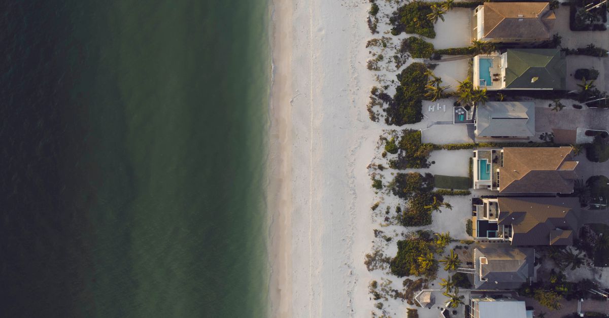 Stunning aerial shot of beachfront homes adjacent to a serene ocean shore.