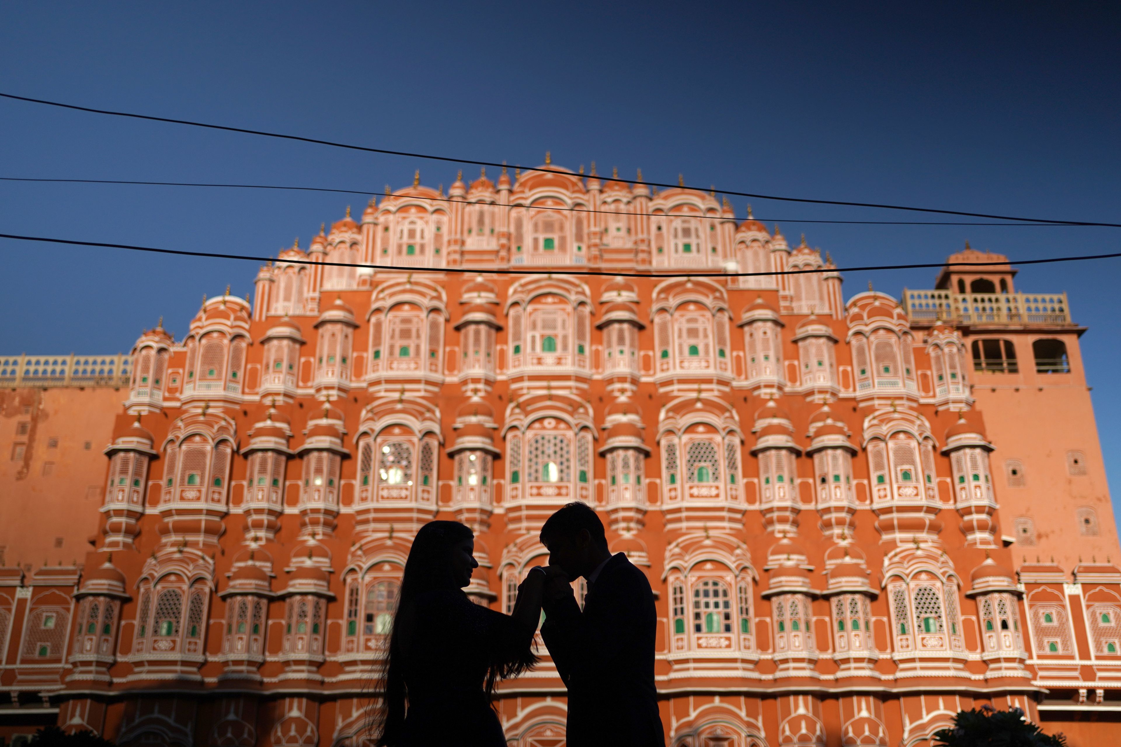 The Hawa Mahal in Jaipur glowing at dusk with a couple in silhouette