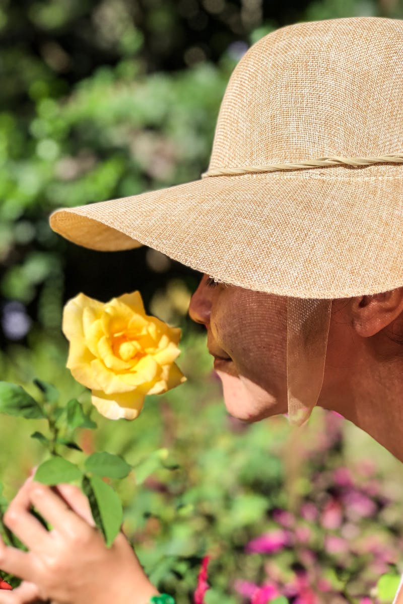 Woman Wearing Sun Hat Smelling Yellow Rose