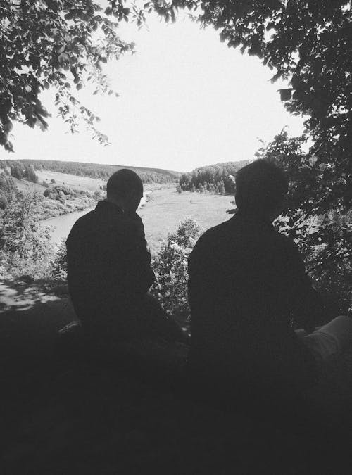 Silhouettes of Men Sitting in Park near Water