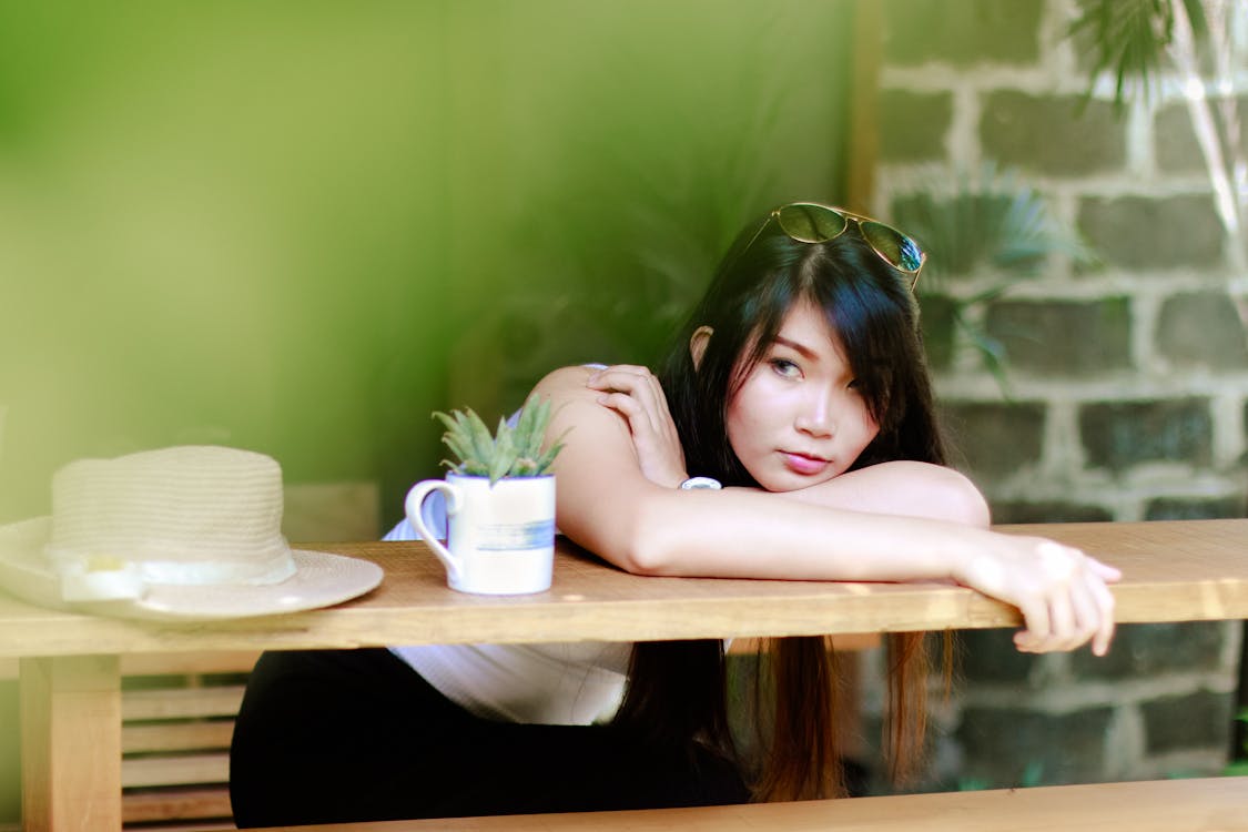 Free Woman Wearing White Shirt Sitting Near Table Stock Photo