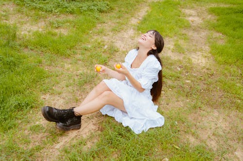 Free Woman in White Dress Sitting on Green Grass Field Stock Photo
