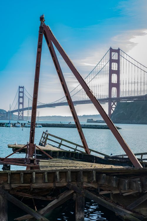 Free A picturesque view of the iconic Golden Gate Bridge with a dilapidated wooden pier in the foreground. Stock Photo