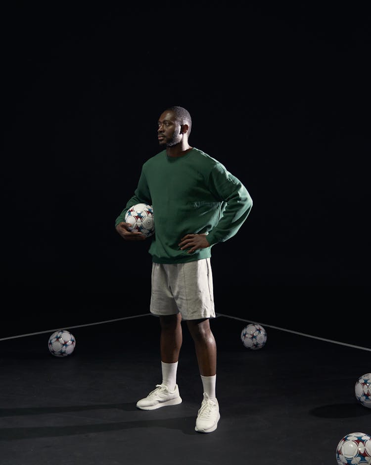 Man Wearing A Green Sweater Holding A Soccer Ball