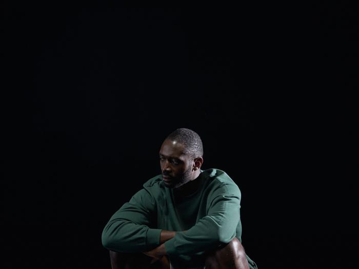 Athlete crouching with footballs in a studio