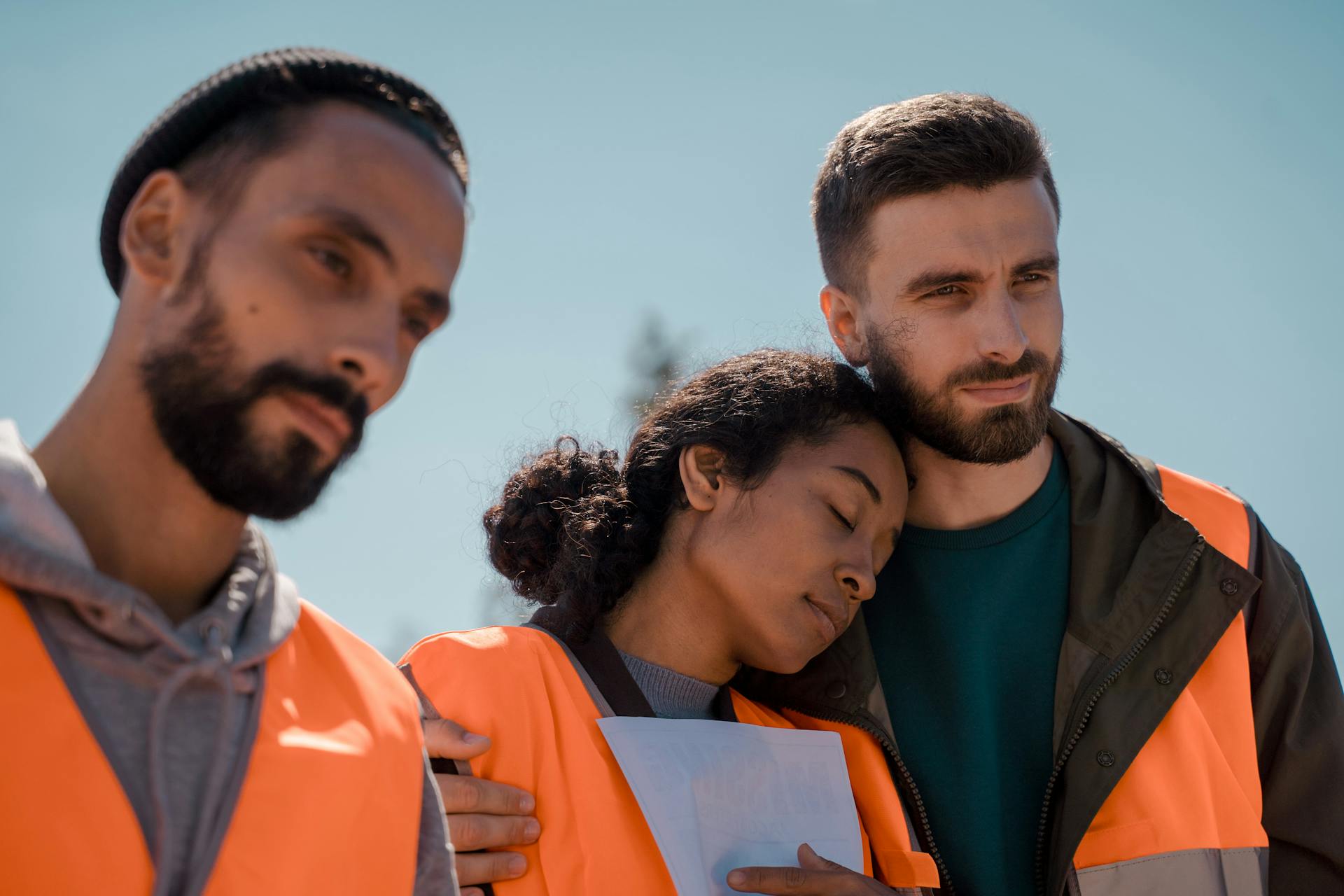 A diverse group of volunteers wearing safety vests outdoors, showing solidarity and teamwork.